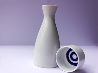 white sake set from a bottle and a cup with blue stripes on white background