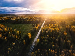 Aerial view of road in beautiful autumn forest at sunset in rural Finland.
