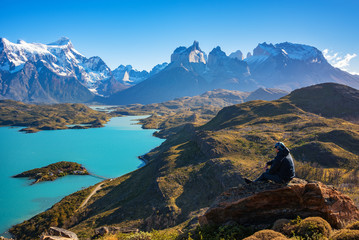 Hiker at mirador condor enjoying amazing view of Los Cuernos rocks and Lake Pehoe in Torres del Paine national park, Patagonia, Chile