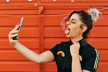 alternative girl shows tongue to her mobile phone - lifestyle concept