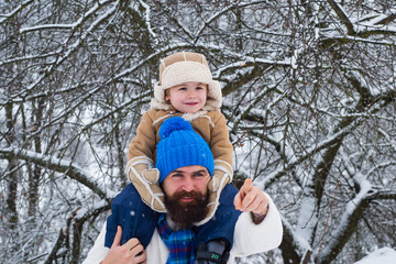 Merry Christmas and Happy New Year. Portrait of happy father giving son piggyback ride on his shoulders and looking up. Child sits on the shoulders of his father.