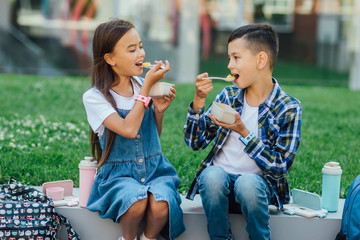 Picnic time. Happy two children with healthy and harmful snacks outside. Child eating maize. Concept of healthy nutrition. Smart watch.