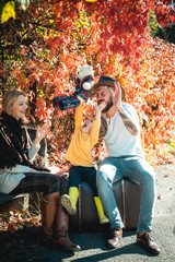 Autumn family. Young father and mother playing with their cute and little son. The season outside with fall activities, searching for fall colors, playing with teddy bear.