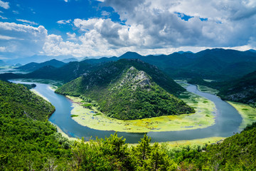 Montenegro, Crnojevica river bend called pavlova strana flowing through green natural mountains of skadar valley into scutari lake national park - obrazy, fototapety, plakaty