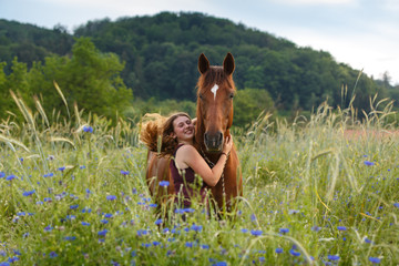 Mädchen mit Pferd im Kornblumenfeld