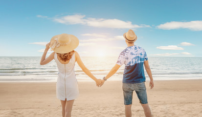 Young happy couple on seashore. Vacation couple walking on beach together in love holding around...