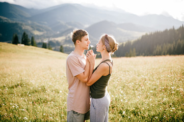 Lifestyle loving couple hugging at nature among mountains in summer.