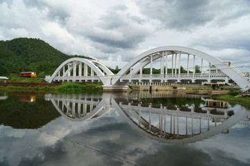 Diesel locomotive passing the Tha Chom Phu railway bridge or white bridge