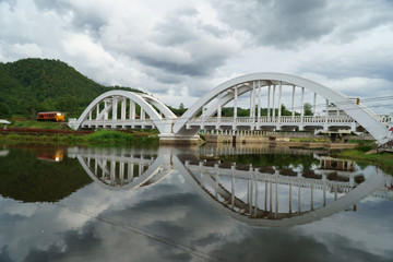 Diesel locomotive passing the Tha Chom Phu railway bridge or white bridge
