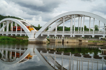Diesel locomotive passing the Tha Chom Phu railway bridge or white bridge