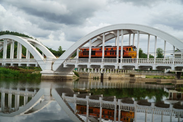 Diesel Train passing the Tha Chom Phu railway bridge or white bridge