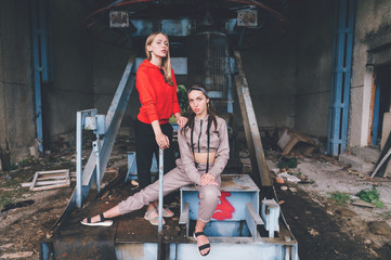 Stylish female couple posing at abandoned cableway station