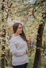 Close up portrait of a Beautiful girl in white sweater near colorful autumn leaves. Artwork of romantic woman .Pretty tenderness model smiling
