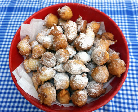 Bowl full of homemade fritters powdered with icing sugar on the vintage kitchen dish towel