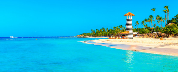 Panoramic view of the tropical beach with lighthouse in Dominican Republic. Coconut Palm trees on white sandy beach. - obrazy, fototapety, plakaty