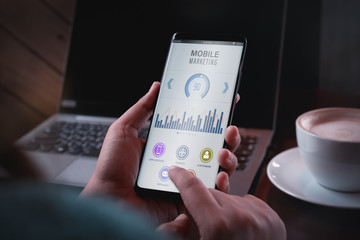 Mobile marketing and customer data analytics concept. Close up Two hand holding smart phone with Mobile Marketing appliaction. Marketing Strategy Connecting Digital via mobile devices Concept.