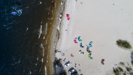 Aerial view of many people who make kitesurfing activity  on beach 