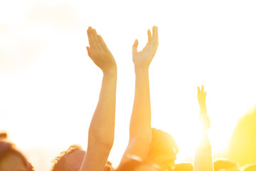 People raised their hands and dance in the open air concert in the setting sun