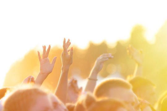 People raised their hands and dance in the open air concert in the setting sun