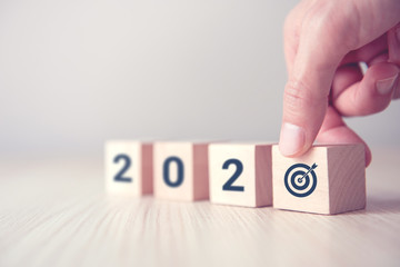 Hand holding wood wooden cubes with New year 2020 and goal icon concept.
