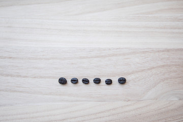 Line of coffe beans on a natural wooden background