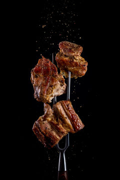 Fork with pieces of delicious barbecued meat on black