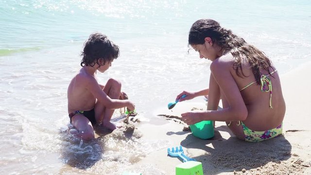 4K Happy sister and little brother build a sand castle on the beach of the Black Sea. motion stock footage video