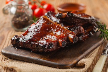 Roasted pork ribs in a bbq sauce. Served on a wooden board. Front view.