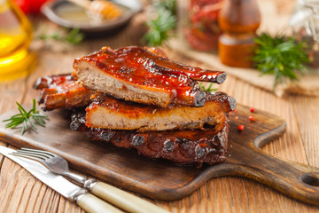 Roasted pork ribs in a bbq sauce. Served on a wooden board. Front view.