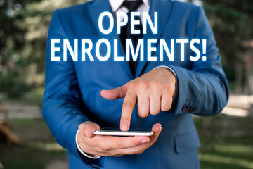 Writing note showing Open Enrolments. Business concept for when employees may make changes to elected fringe benefit Businessman with pointing finger in front of him