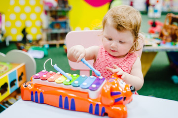 Happy little kid, baby girl 1-2 years, children plays a musical instrument xylophone in game...