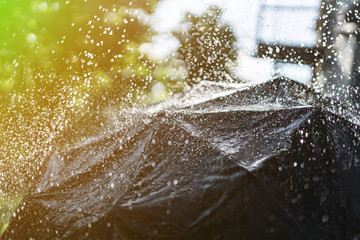 close up black umbrella with splashes and raindrops during heavy rain outdoor
