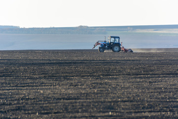 Farm Tractor with plow in a field on a Farm in the sunny day. Farmer in tractor preparing land. It...