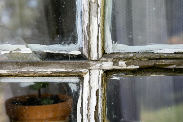 Old window pane with peeled of white color, crack in the glass