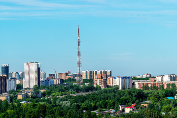 Fototapeta premium In the center of the image is an old television center. To the right and left of it are high-rise buildings. In the foreground trees, one of the streets. Early morning, June.