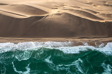 Aerial view of Skeleton coast sand dunes meeting the waves of Atlanic ocean. Skeleton coast,...