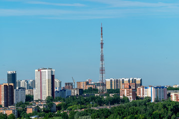 Fototapeta na wymiar Before us is the old TV tower and the surrounding high-rise buildings. In the foreground one-storey houses on the outskirts of the city of Perm. Early June morning.