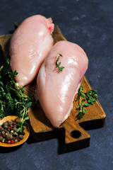 raw chicken breast and fresh thyme on a cutting board, vertical top view