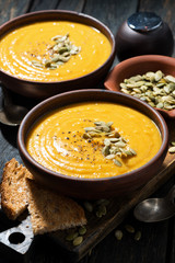 pumpkin soup with toasts on wooden table, vertical