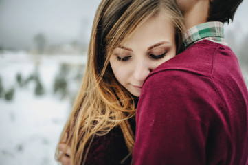 Two lovers are hugging in Saint Valentine's Day. Young romantic couple is having fun outdoors in winter park before Christmas. Enjoying spending time together in New Year Eve.