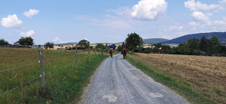 Feldweg mit zwei Reitern auf zwei Pferden
