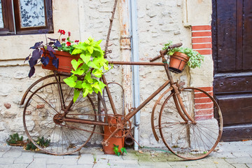 Vintage bicycle with basket of flowers in front of the old rustic house in France, Europe.