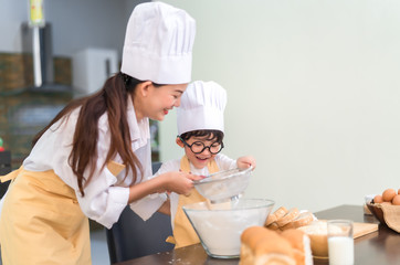Happy family asian mom and son making bakery cake prepare delicious sweet food in the kitchen room for dinner lifestyle.