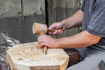 Craftsman hands working with a chisel on board