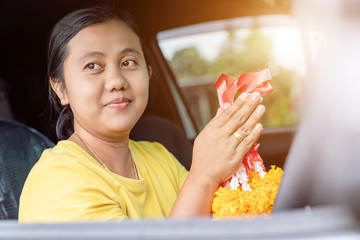 Woman flower garland in hand and praying in the new car for lucky, safety in Thai style