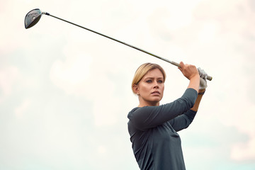 Portrait of a beautiful woman playing golf on a green field outdoors background. The concept of...