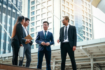 Four Asian businessmen stand to discuss real estate investment.