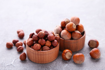 Delicious hazelnut in the wooden bowl on grey background
