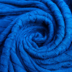 Fototapeta na wymiar Rolled-up blue plaid, knitted pigtail. Wool texture for background. Soft focus.