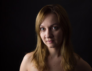 Naklejka premium portrait of young woman, no make up, low key, brown dark hair, natural looking making expressions 